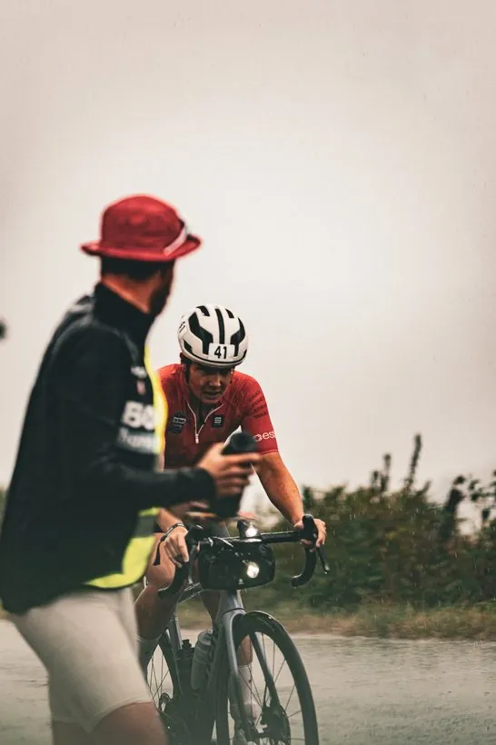 Betreuer mit rotem Hut spricht mit Lisa auf dem Rad