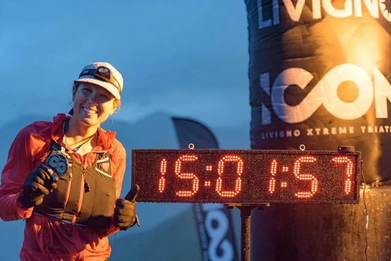 Lisa Wiestner im Ziel des ICON Livigno Xtreme Triathlon vor der Zeitanzeige 15:01:57